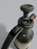 Close-up of a black and gray spray bottle with a red cap on a light gray background