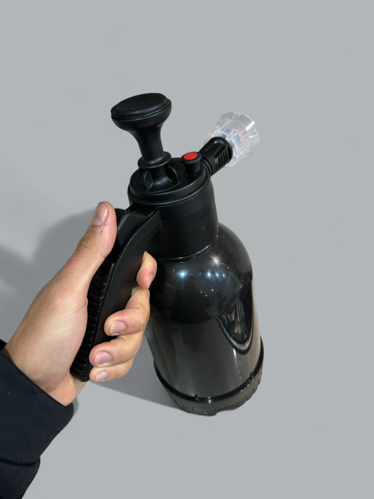 Black hand pump held by a person against a gray background