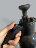 Hand holding a black pump with a red button against a gray background