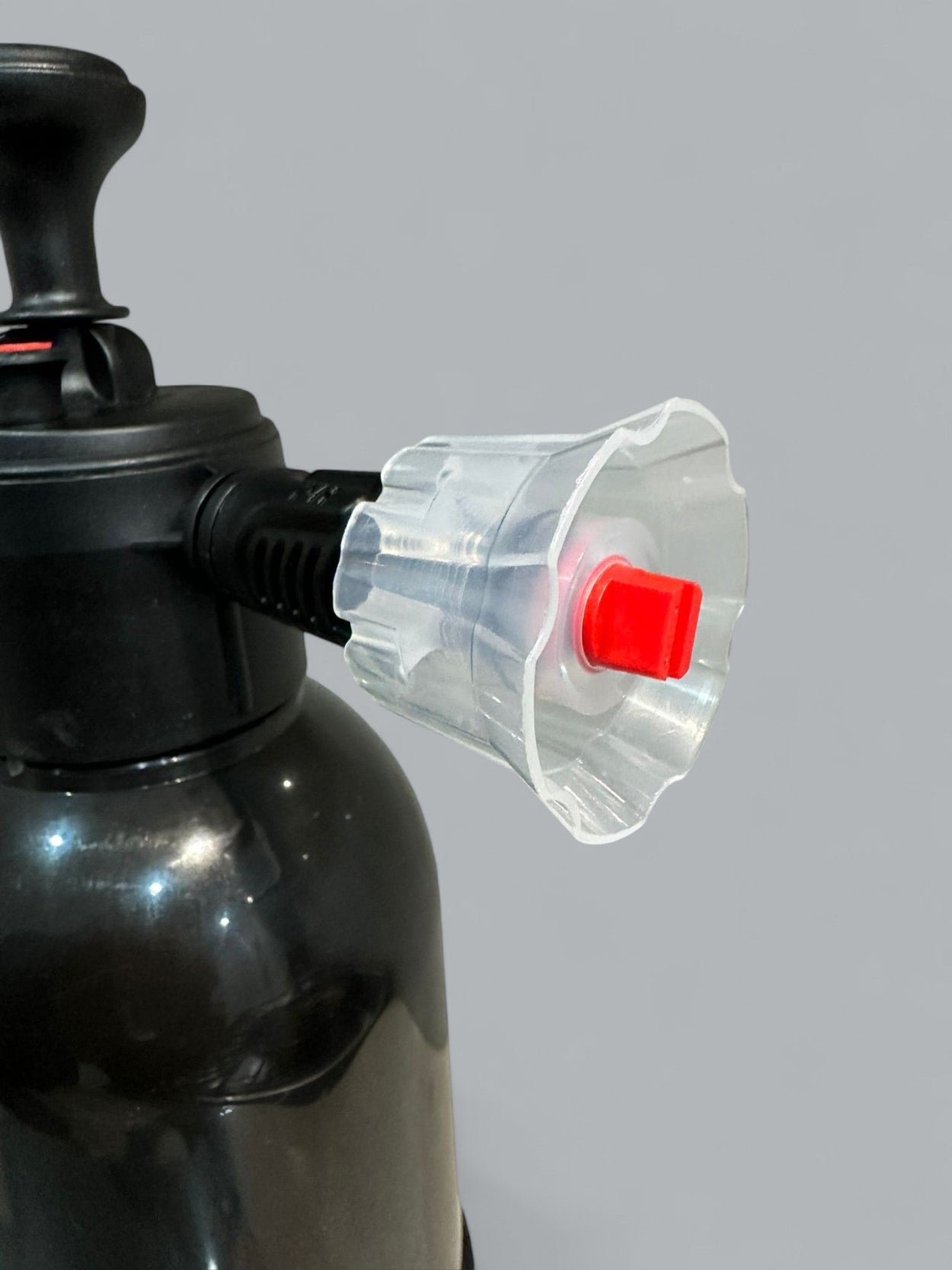 Black air compressor with a clear plastic nozzle and red button on a gray background